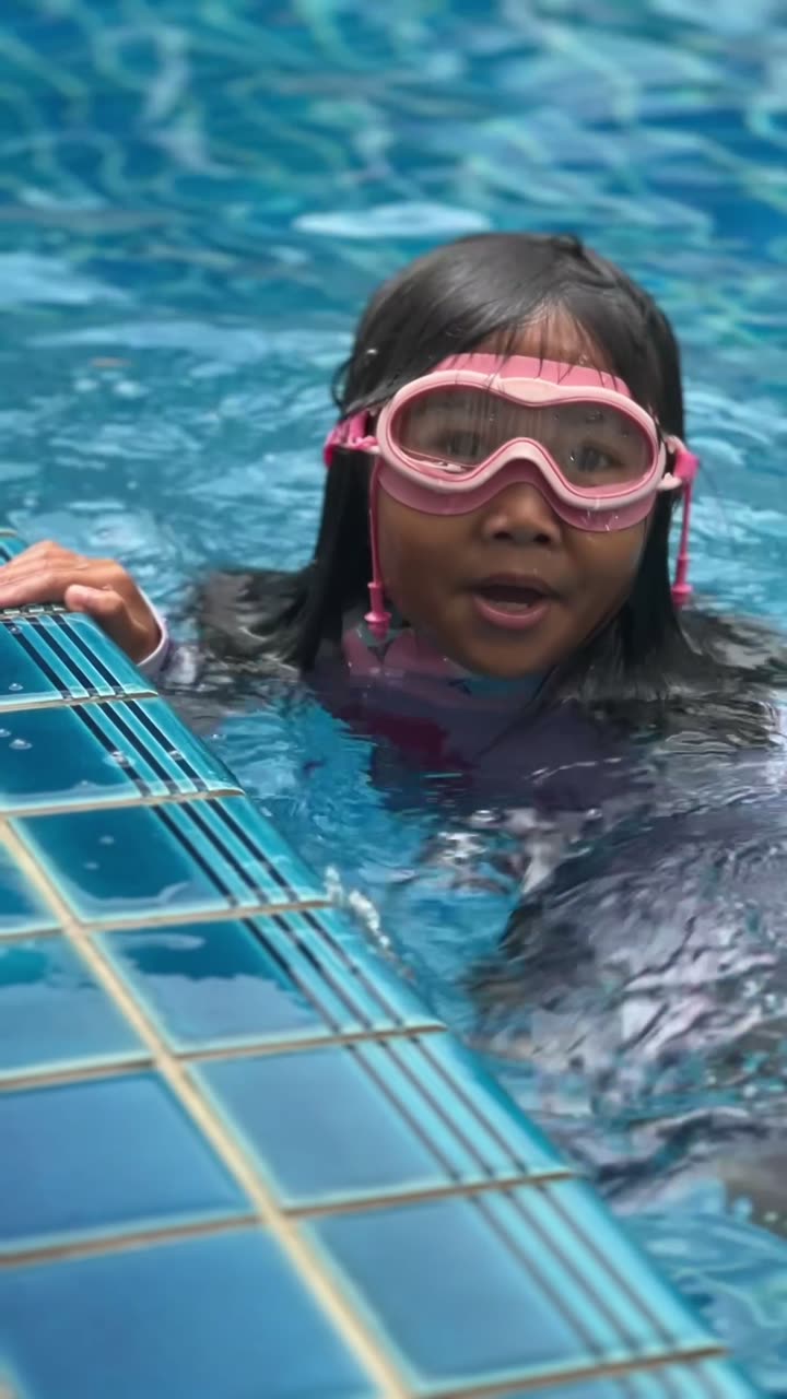 Zara in the pool wearing pink goggles
